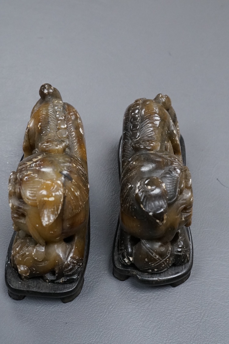 A pair of Chinese soapstone figures of lion dogs, on wood stands, 11cm wide